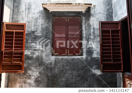 Traditional architectural details of Mandarin House built in 1869 with carved wooden window shutters on grunge wall Traditional architectural details of Mandarin House built in 1869 with carved wooden window shutters on grunge wall 142113147