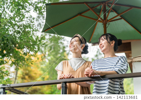 一位年輕的亞洲女性在養老金/小屋/小屋的木甲板上放鬆 一位年輕的亞洲女性在養老金/小屋/小屋的木甲板上放鬆 142113681