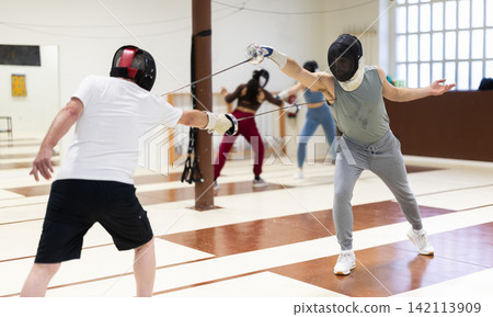 Men and women in helmets practicing sparring fights Men and women in helmets practicing sparring fights 142113909