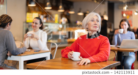 Senior woman whiles away time and waits for meeting in chain cafe 142113911