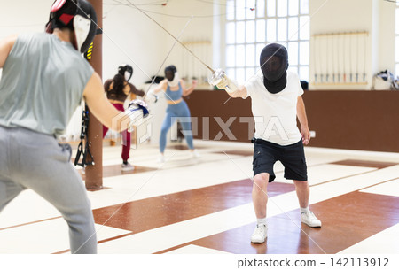 men in protective equipment conduct a training fencing match men in protective equipment conduct a training fencing match 142113912