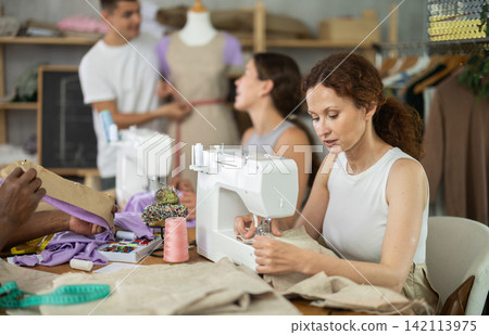 Participants in coterie practice sewing, chatting and talking, work with mannequin 142113975