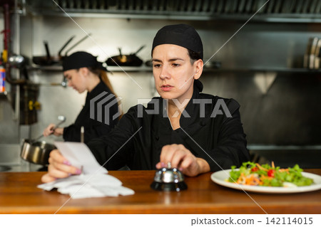 Chef checking orders and giving out meal Chef checking orders and giving out meal 142114015