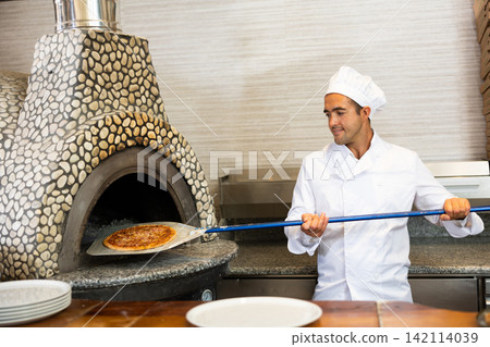 Skilled man chef preparing pizza in restaurant Skilled man chef preparing pizza in restaurant 142114039