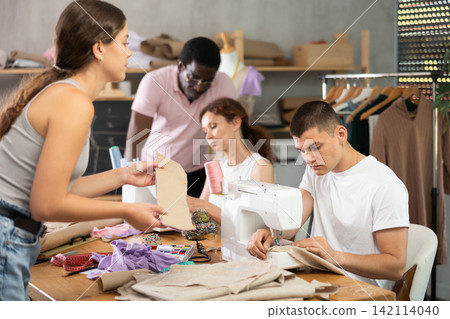 Engaged guy stitching fabric on machine in sewing class for adults 142114040