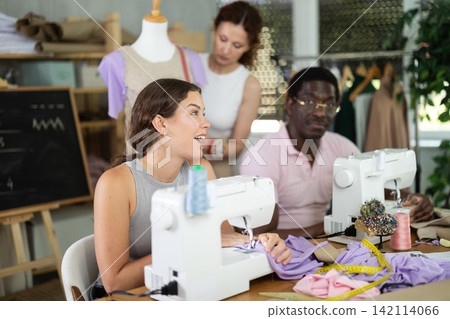 Young girl talking and sewing, other working with mannequin Young girl talking and sewing, other working with mannequin 142114066