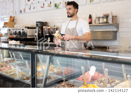 guy working in a cafe offers ice cream 142114127