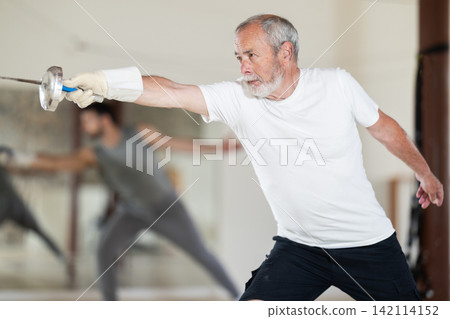 Elderly man attending fencing lessons Elderly man attending fencing lessons 142114152