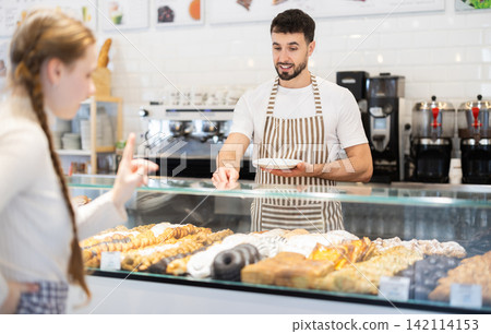 Bakery salesman offers to buy delicious pastry Bakery salesman offers to buy delicious pastry 142114153