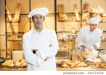 Confident male baker welcoming everyone into his bakery Confident male baker welcoming everyone into his bakery 142114158