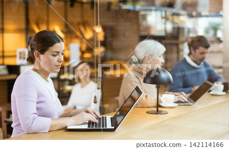 Woman spending time in cozy coffeehouse with laptop and coffee Woman spending time in cozy coffeehouse with laptop and coffee 142114166