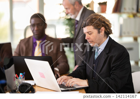 European man working on laptop with room in office European man working on laptop with room in office 142114167