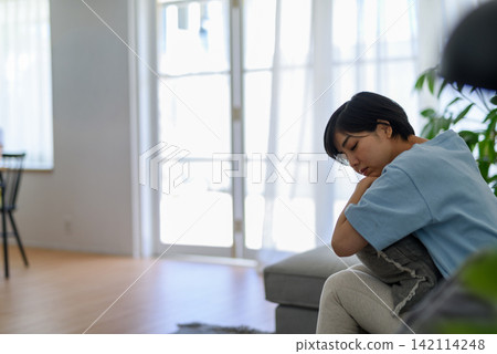 A sad-looking young woman slumped on a sofa. A sad-looking young woman slumped on a sofa. 142114248