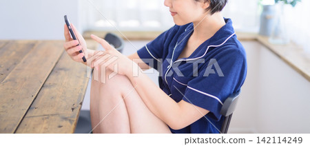 A woman checks her phone for messages during breakfast. A woman checks her phone for messages during breakfast. 142114249