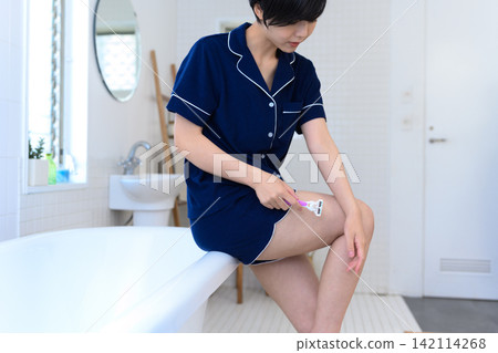 一位女士在浴室裡去除腿毛。 一位女士在浴室裡去除腿毛。 142114268