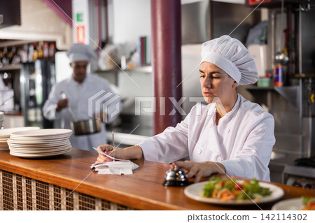 Chef checking orders and giving out meal 142114302
