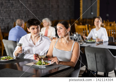 Young man and woman having dinner in restaurant 142114304