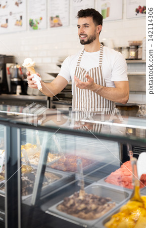 Guy stands at counter selling ice cream Guy stands at counter selling ice cream 142114306