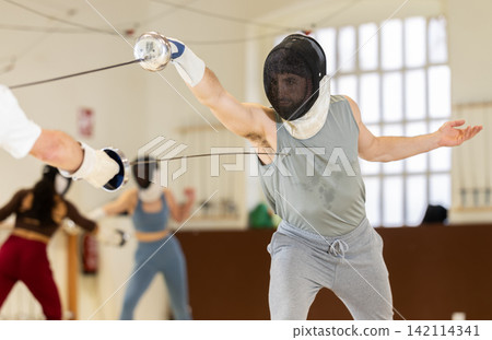 Group of fencers trains in duels and works out blows on the pillows in gym Group of fencers trains in duels and works out blows on the pillows in gym 142114341