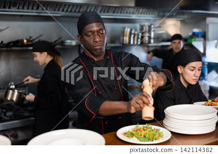 Chef seasoning salad before giving it out Chef seasoning salad before giving it out 142114382