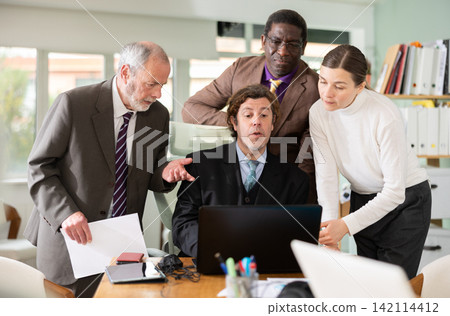 Group of office employees look at the notebook together and rejoice Group of office employees look at the notebook together and rejoice 142114412