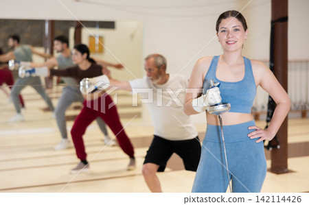 Young woman is engaged in fencing in a modern sports club Young woman is engaged in fencing in a modern sports club 142114426