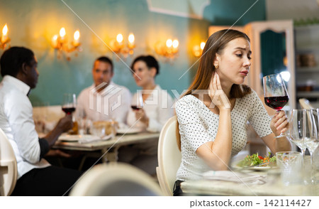Elegant upset woman is expecting man for dinner in restaurante Elegant upset woman is expecting man for dinner in restaurante 142114427