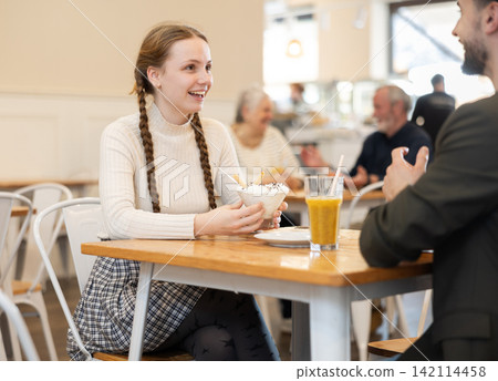 Mature father chats with his teenage daughter at a cafe table for breakfast with ice cream 142114458