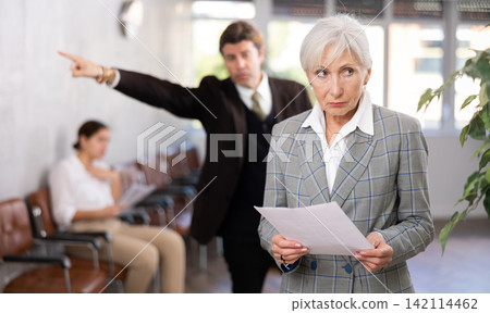 Upset elderly woman with documents in office Upset elderly woman with documents in office 142114462