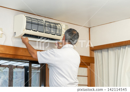 Air conditioner cleaning; a man from the air conditioner maintenance company. Air conditioner cleaning; a man from the air conditioner maintenance company. 142114545