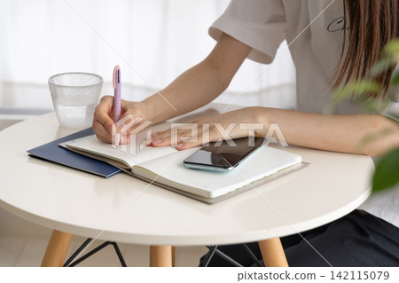 The image of a woman writing in a notebook in her daily life The image of a woman writing in a notebook in her daily life 142115079