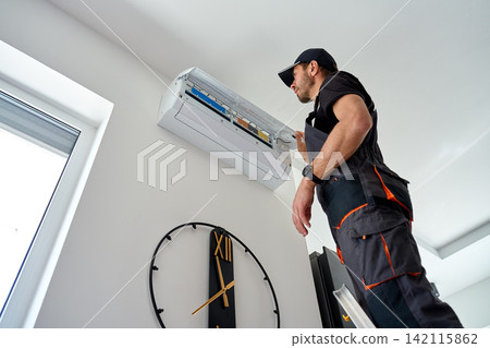 Air conditioner technician inspecting open wall mounted unit at home Air conditioner technician inspecting open wall mounted unit at home 142115862