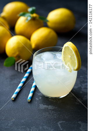 Lemonade with fresh lemon in glasses on dark background. Cold refreshing lemonade for summer party and fun. Lemonade with fresh lemon in glasses on dark background. Cold refreshing lemonade for summer party and fun. 142116177
