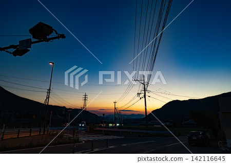 熊本縣立野市的日落景象,以道路交叉口和電線為背景。 熊本縣立野市的日落景象,以道路交叉口和電線為背景。 142116645