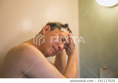 A man in his 40s shampooing his hair in the bathroom. A man in his 40s shampooing his hair in the bathroom. 142117628