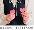 A woman holding two pink hearts 142117826