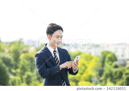 A businessman operating a smartphone A businessman operating a smartphone 142118051