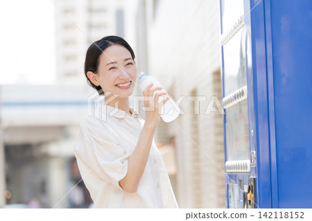 A woman drinking water she bought from a vending machine. A woman drinking water she bought from a vending machine. 142118152