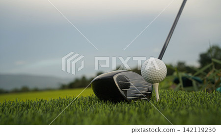 Golf clubs and balls on a green lawn in a beautiful golf course with morning sunshine. Golf clubs and balls on a green lawn in a beautiful golf course with morning sunshine. 142119230