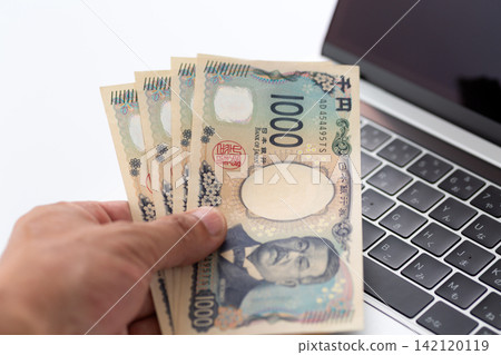 一手拿著4000日元,放在電腦前。 一手拿著4000日元,放在電腦前。 142120119