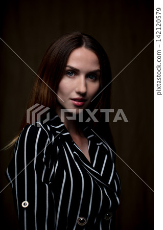 portrait of a young beautiful woman on a dark background portrait of a young beautiful woman on a dark background 142120579