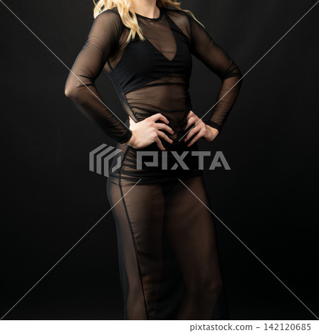 Dancer wearing transparent black dress posing on black background Dancer wearing transparent black dress posing on black background 142120685