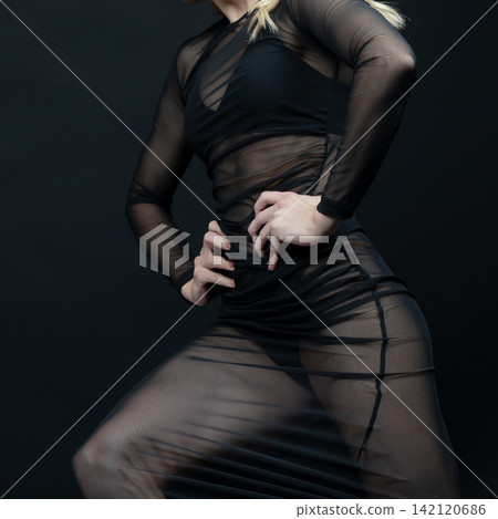 Dancer wearing transparent black dress posing on black background Dancer wearing transparent black dress posing on black background 142120686