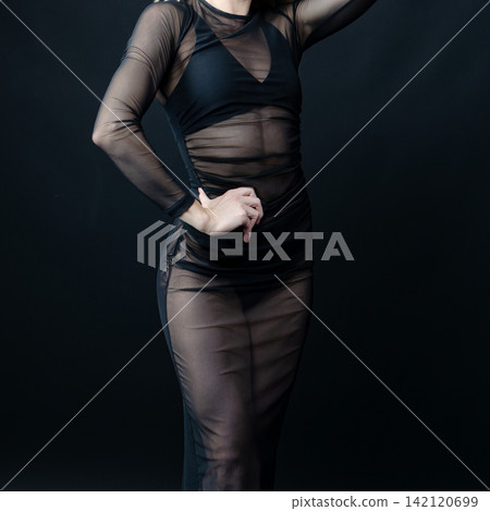 Dancer wearing transparent black dress posing on black background Dancer wearing transparent black dress posing on black background 142120699