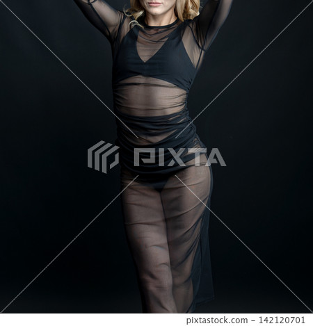 Dancer wearing transparent black dress posing on black background Dancer wearing transparent black dress posing on black background 142120701
