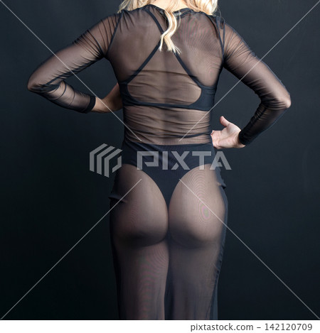 Dancer wearing transparent black dress posing on black background Dancer wearing transparent black dress posing on black background 142120709