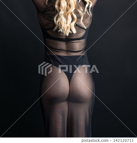 Dancer wearing transparent black dress posing on black background Dancer wearing transparent black dress posing on black background 142120711