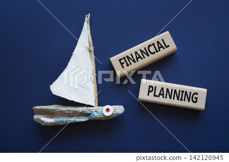 Financial Planning symbol. Concept word Financial Planning on wooden blocks. Beautiful deep blue background with boat. Business and Financial Planning concept. Copy space Financial Planning symbol. Concept word Financial Planning on wooden blocks. Beautiful deep blue background with boat. Business and Financial Planning concept. Copy space 142120945