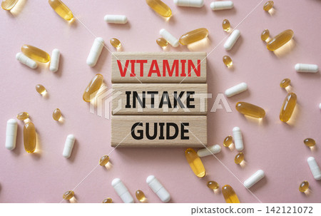 Vitamin intake guide symbol. Concept words Vitamin intake guide on wooden blocks. Beautiful pink background with pills. Healthcare and Vitamin intake guide concept. Copy space. 142121072