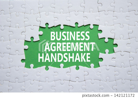 Business Agreement Handshake symbol. White puzzle with words Business Agreement Handshake. Beautiful green background. Business and Business Agreement Handshake concept. Copy space. Business Agreement Handshake symbol. White puzzle with words Business Agreement Handshake. Beautiful green background. Business and Business Agreement Handshake concept. Copy space. 142121172